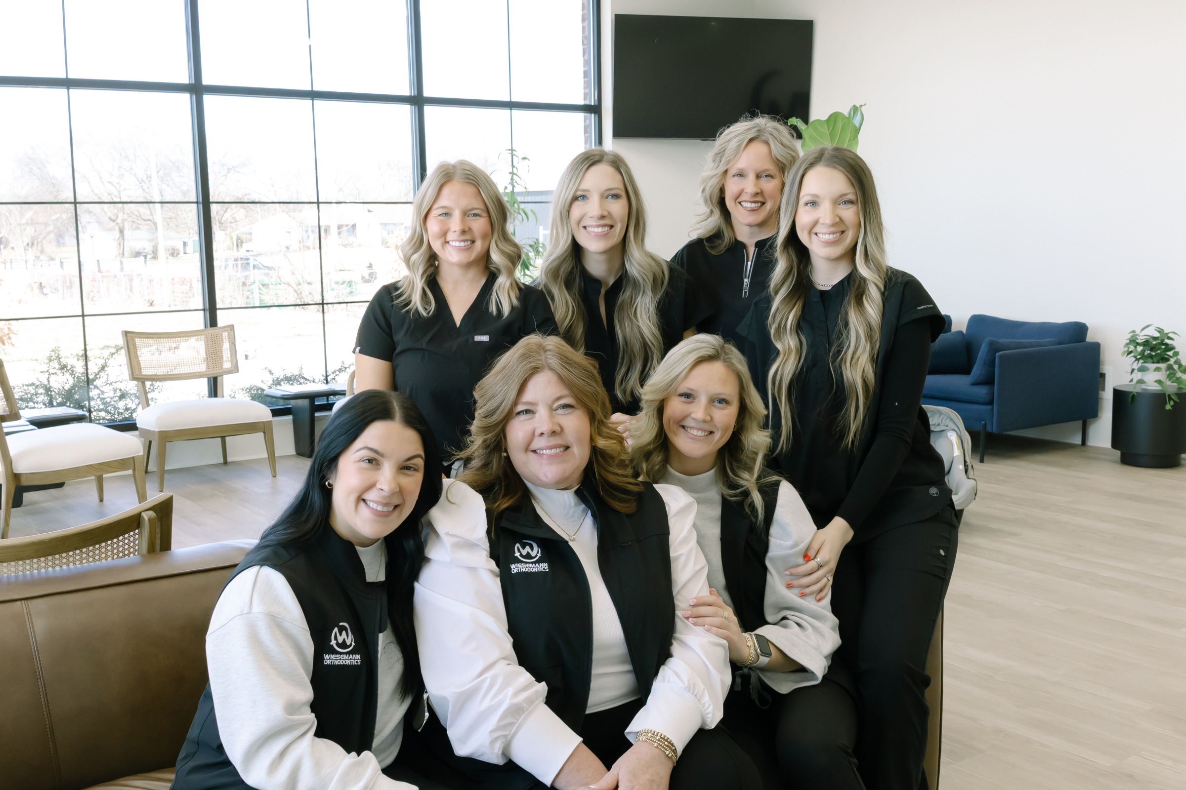 Group of orthodontic staff members at Wiesemann Orthodontics, smiling and dressed in uniforms, in a modern clinic setting, emphasizing a welcoming atmosphere for patients seeking braces and Invisalign in Russellville and Bowling Green.