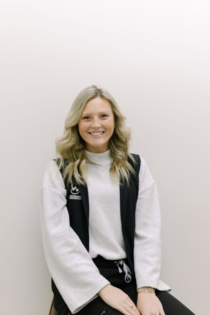Hannah, clinical assistant at Wiesemann Orthodontics, smiling in a gray sweater and black vest, representing the friendly team dedicated to braces and Invisalign in Bowling Green, KY.