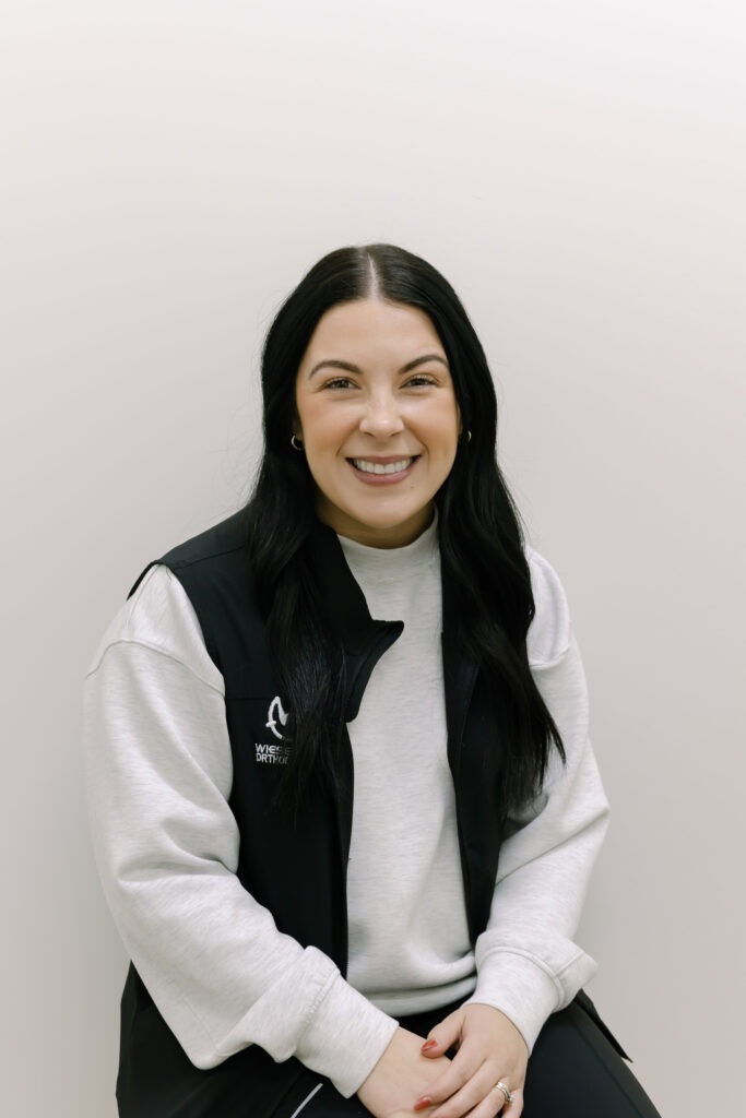 Clinical Assistant Kennedy from Wiesemann Orthodontics smiling in a professional setting, representing the friendly team dedicated to braces and Invisalign in White House, TN.