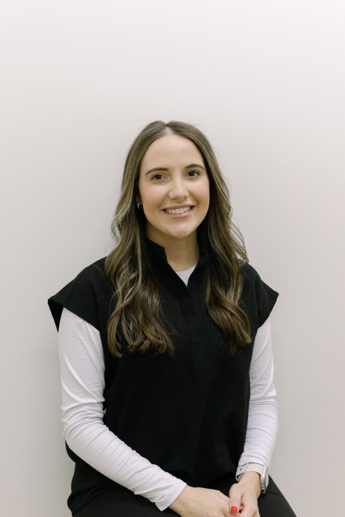 Malorie, clinical assistant at Wiesemann Orthodontics, smiling in a black top against a neutral background, representing the friendly team dedicated to braces and Invisalign in Russellville, KY.