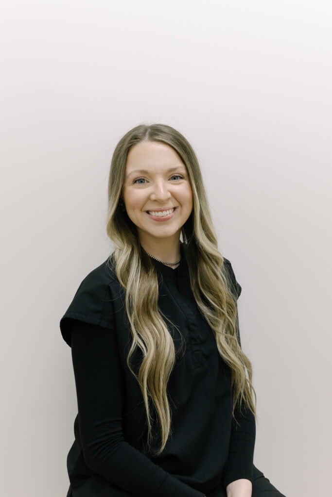 Sydney, clinical assistant at Wiesemann Orthodontics, smiling in a black top, promoting friendly orthodontic care in Bowling Green, KY, specializing in braces and Invisalign.